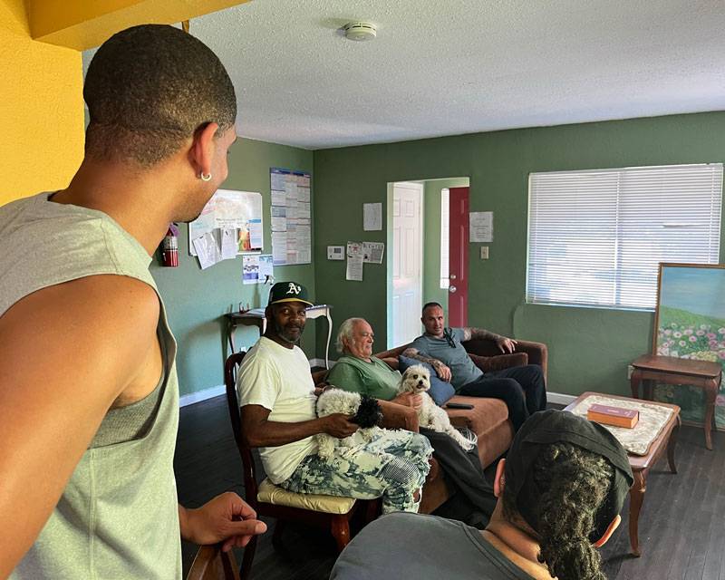 Image of men in living room of Retraining The Village Residential Recovery home in East Palo Alto, California